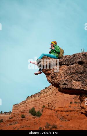 Frau mit Rucksack sitzt auf Felsen am roten Canyon Stockfoto