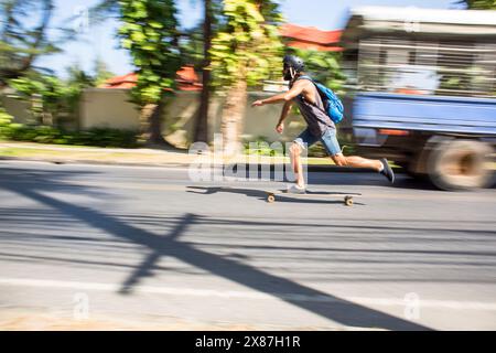 Verschwommene Bewegung auf dem Longboard des jungen Mannes auf der Straße Stockfoto