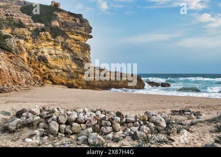 Strand mit Steinen, Kalksteinklippen, Wellen und blauem Meer von Praia do Figueira, zwischen Sagres und Lagos, Algarve, Portugal Stockfoto