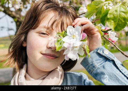 Lächelndes Mädchen, das das Auge mit Blumen bedeckt Stockfoto