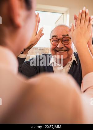 Glücklicher Seniorenmann, der High-Five dem Arzt im Pflegeheim gibt Stockfoto