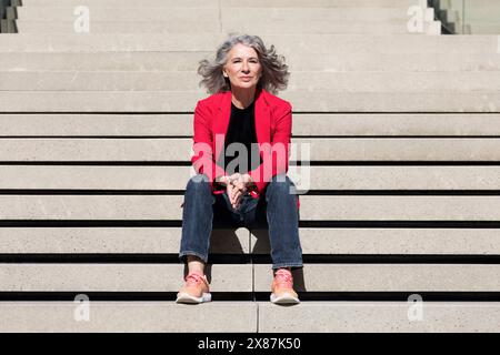 Ältere Geschäftsfrau mit gefesselten Händen auf der Treppe sitzend Stockfoto