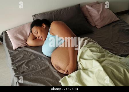 Schwangere Frau, die morgens zu Hause im Bett schläft Stockfoto