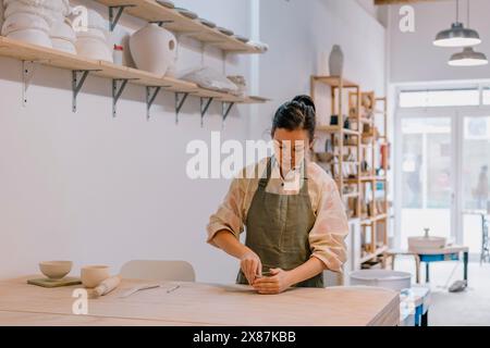 Geschickte Handwerker, die Ton Formen, stehen am Tisch am Töpferarbeitsplatz Stockfoto