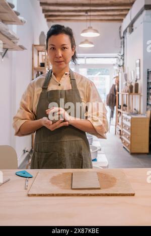 Geschickte Handwerker, die Ton Formen, stehen am Tisch am Töpferarbeitsplatz Stockfoto