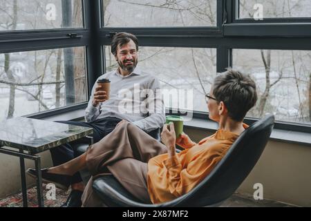 Lächelnder Geschäftsmann, der eine Kaffeepause macht und mit einem Kollegen im Büro diskutiert Stockfoto