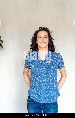 Lächelnde Frau, die vor der Wand steht Stockfoto