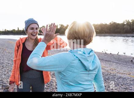 Glückliche junge Frau, die Großmutter in der Nähe des Flusses High-Five gibt Stockfoto