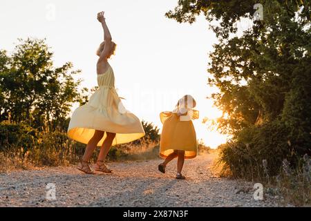 Mutter und Tochter tanzen bei Sonnenuntergang auf dem Fußweg Stockfoto