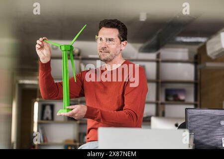 Ingenieur, der das Modell einer umweltfreundlichen Windkraftanlage im Büro analysiert Stockfoto