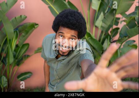 Lächelnder Afro-Mann, der in der Nähe von Palmen gestickt hat Stockfoto