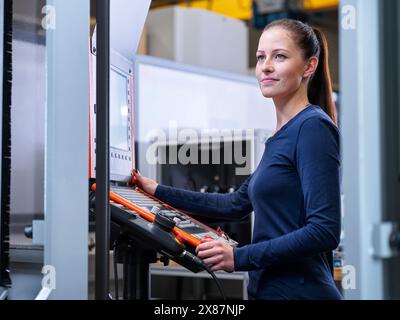 Lächelnder Ingenieur, der in der Nähe des CNC-Maschinenteils steht Stockfoto