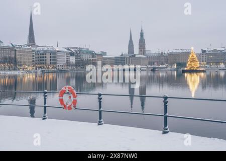 Deutschland, Hamburg, im Winter hängt der Rettungsgürtel auf dem Geländer über der Binnenalster mit einem Weihnachtsbaum im Hintergrund Stockfoto