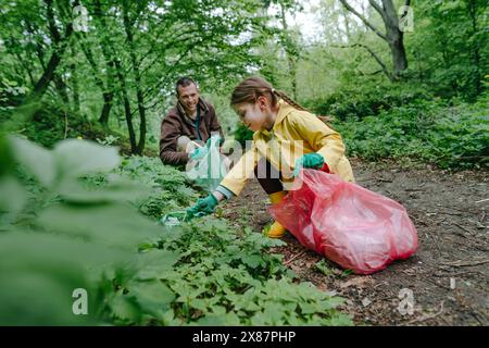 Glücklicher Vater und Tochter sammeln Plastikmüll im Wald Stockfoto