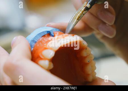 Ein Zahntechniker verwendet Präzisionswerkzeuge, um Prothesen zu verlöten und zu Formen und zeigt handwerkliches Können in der Dentalherstellung. Stockfoto