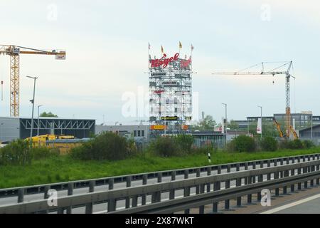 Weimar, Deutschland - 7. Mai 2023: Neben einer Autobahn mit Kränen und einem markanten Piegel-Schild über einem hohen Gebäude auf einer c Stockfoto