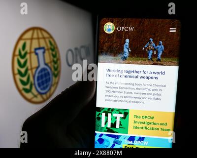 Person, die ein Smartphone mit einer Webseite der Organisation für das Verbot chemischer Waffen (OVCW) mit Logo hält. Konzentrieren Sie sich auf die Mitte des Telefondisplays. Stockfoto