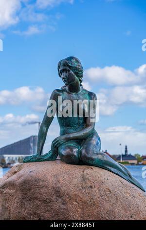 KOPENHAGEN, DÄNEMARK - 14. APRIL 2024: Bronzestatue der kleinen Meerjungfrau, die auf einem Felsen am Langelinie Pier von Edvard Eriksen sitzt, ist eine von Kopenhagen' Stockfoto