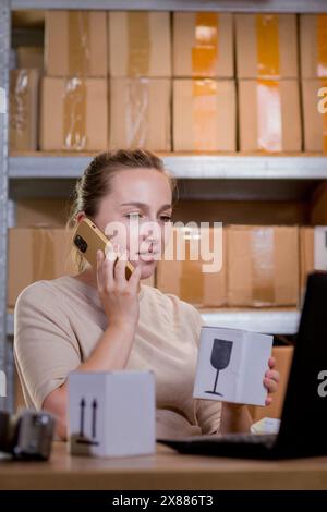 Frau, die ein Mobiltelefon oder Tablet verwendet, um mit Kunden zu kommunizieren. Lieferung von Waren über private Kurierdienste. Konzepte des Online-Verkaufs und weiter Stockfoto