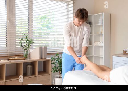 Therapeut beim Massagen des Fußes junger Frau im Spa-Salon Stockfoto