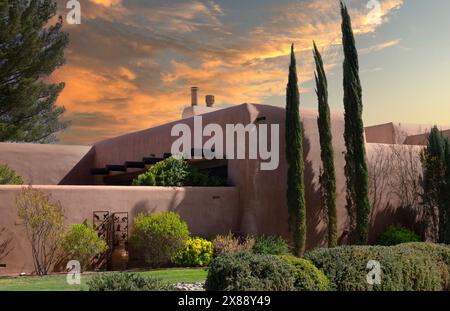 Nahe Sonnenuntergang umrahmt das riesige Haus im Pueblo Revival Stil mit lehmwand zusammen mit hoch aufragenden Zypressen und Landschaftsgestaltung in Las Cruces, NM Stockfoto