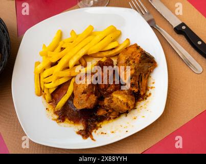 Eine Portion köstliches Hühnchen mit Gewürzen und Knoblauch wird auf einem Teller serviert. Stockfoto