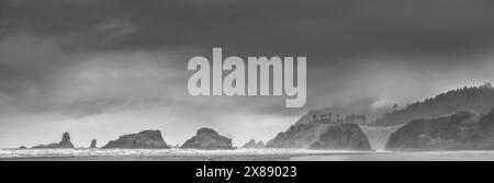 Panorama-Landschaftsfotografie von Meeresstapeln und Felsen im Pazifik am Cannon Beach, Oregon, an einem stürmischen Abend mit einem dramatischen Himmel, stimmungsvoll Stockfoto