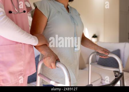 Zu Hause benutzen asiatische junge Krankenschwester und Patienten mittleren Alters Walker Stockfoto