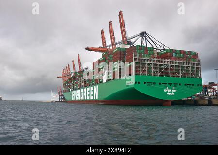 Container auf ein riesiges Frachtschiff laden Stockfoto