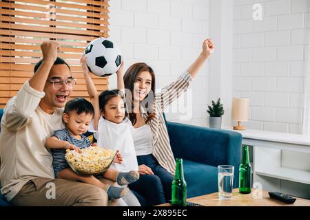 Eine glückliche Familie genießt den Nervenkitzel eines Fußballspiels zu Hause Stockfoto