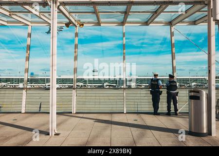 Zwei bewaffnete Flughafenpolizisten beobachten einen Rollweg am Flughafen München, Deutschland, von der Aussichtsplattform des Terminals 2 aus Stockfoto