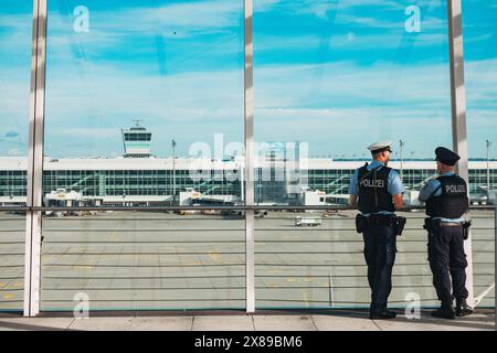 Zwei bewaffnete Flughafenpolizisten beobachten einen Rollweg am Flughafen München, Deutschland, von der Aussichtsplattform des Terminals 2 aus Stockfoto