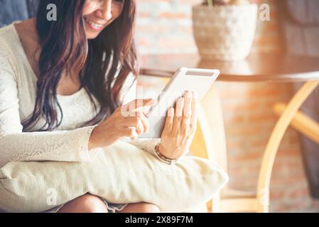 Asiatische Frau, die mit einem Smartphone auf der Online-Website mit einem Smartphone mit einem lächelnden Gesicht einkaufen möchte. Glückliche asiatische Frau, die ihr Handy hält und Post von onl abfragt Stockfoto