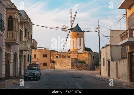 Eine kleine Windmühle ragt über einer Wohnstraße in einer kleinen Stadt auf der Insel Gozo, Malta Stockfoto