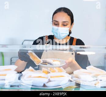 Marokkanische Frau arbeitet in ihrem kleinen marokkanischen Süßwarengeschäft Stockfoto