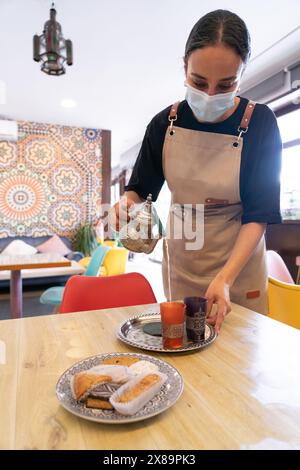 Die marokkanische Kellnerin serviert einen Pfefferminztee in einem marokkanischen Café Stockfoto