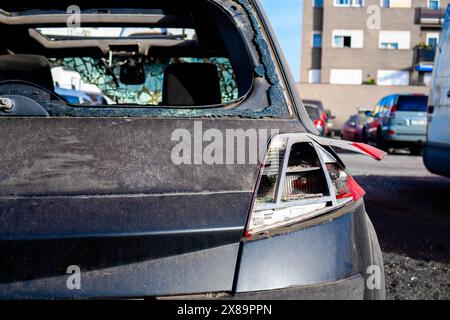 Ein verlassenes Auto mit einer zertrümmerten Windschutzscheibe, das in der städtischen Landschaft vernachlässigt ist. Stockfoto