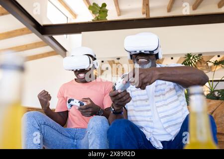 Afrikanisch-amerikanischer Vater und Sohn in VR-Headsets zu Hause, die Spiele genießen Stockfoto