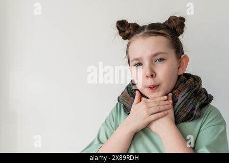 Ein kleines Mädchen mit einer Pille im Mund hält sich an einer Halsschmerzen fest. Leerzeichen für Text. Hochwertige Fotos Stockfoto