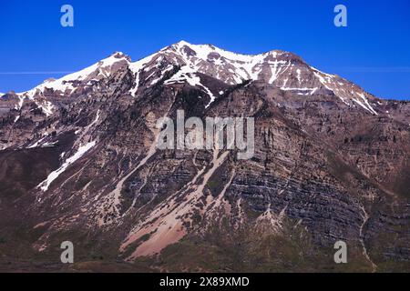 Eine Bergkette mit Schnee auf der Spitze und einem blauen Himmel im Hintergrund. Die Bergkette ist felsig und karg, ohne Vegetation Stockfoto