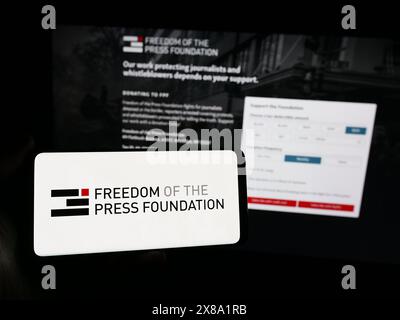 Person, die ein Smartphone mit dem Logo der Organisation Freedom of the Press Foundation (FPF) vor der Website hält. Schwerpunkt auf dem Display des Telefons. Stockfoto