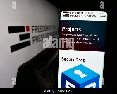 Person mit Smartphone und Website der Organisation Freedom of the Press Foundation (FPF) vor dem Logo. Konzentrieren Sie sich auf die Mitte des Telefondisplays. Stockfoto