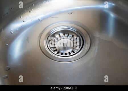 Waschbecken aus Edelstahl und Wasserablauf in einer modernen Küche, Wasserfluss in der Küchenspüle, Wasser fließt aus dem Abfluss Stockfoto