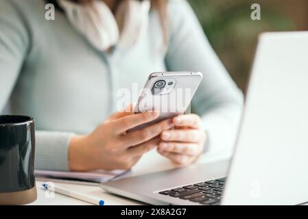 Kiew, Ukraine. Januar 2022. Nahaufnahme einer Frau mit Handy und Laptop auf weißem Schreibtisch im modernen Büro. Stockfoto