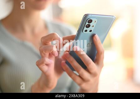 Polen, Posen - 29. märz 2022. Close-up-Frau benutzt das moderne Telefon OnePlus 9r, um zu Hause durch die Neuigkeiten zu blättern. So schreiben Sie eine Nachricht: Stockfoto