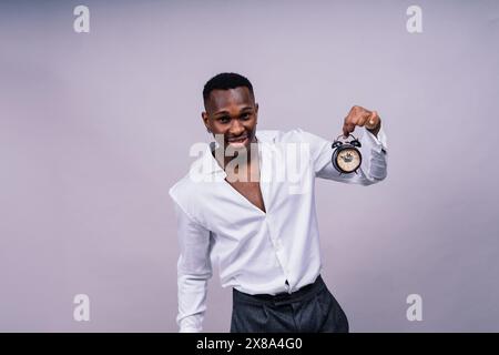 Zeitmanagementkonzept. Schockierter Schwarzer, der die Wanduhr in der Hand hält, läuft die Zeit davon. Stockfoto