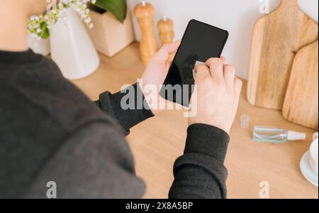 Globale Coronavirus-Epidemie. Mann desinfiziert Telefon mit antiseptischem Feuchttuch. Coronavirus-Prophylaxe. Prävention von Krankheit Coronavirus nach öffentlichem Platz. Stockfoto