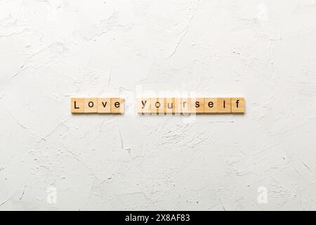 Liebe dich selbst Wort auf Holzblock geschrieben. Love Yourself Text auf Zementtisch für Ihr Design, Draufsicht Konzept. Stockfoto