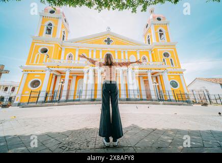 Touristenfrau, die Arme vor einer Kathedrale auf einem Touristenplatz spreizt. Glücklicher Tourist auf einem Touristenplatz. Granada, Nicaragua, Mittelamerika Stockfoto