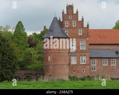 Eine Ziegelburg mit dominantem Rundturm, umgeben von Natur, eine rote Ziegelburg mit runden Türmen und mit einem Graben und vielen Bäumen, Herten, Deutschland, Stockfoto